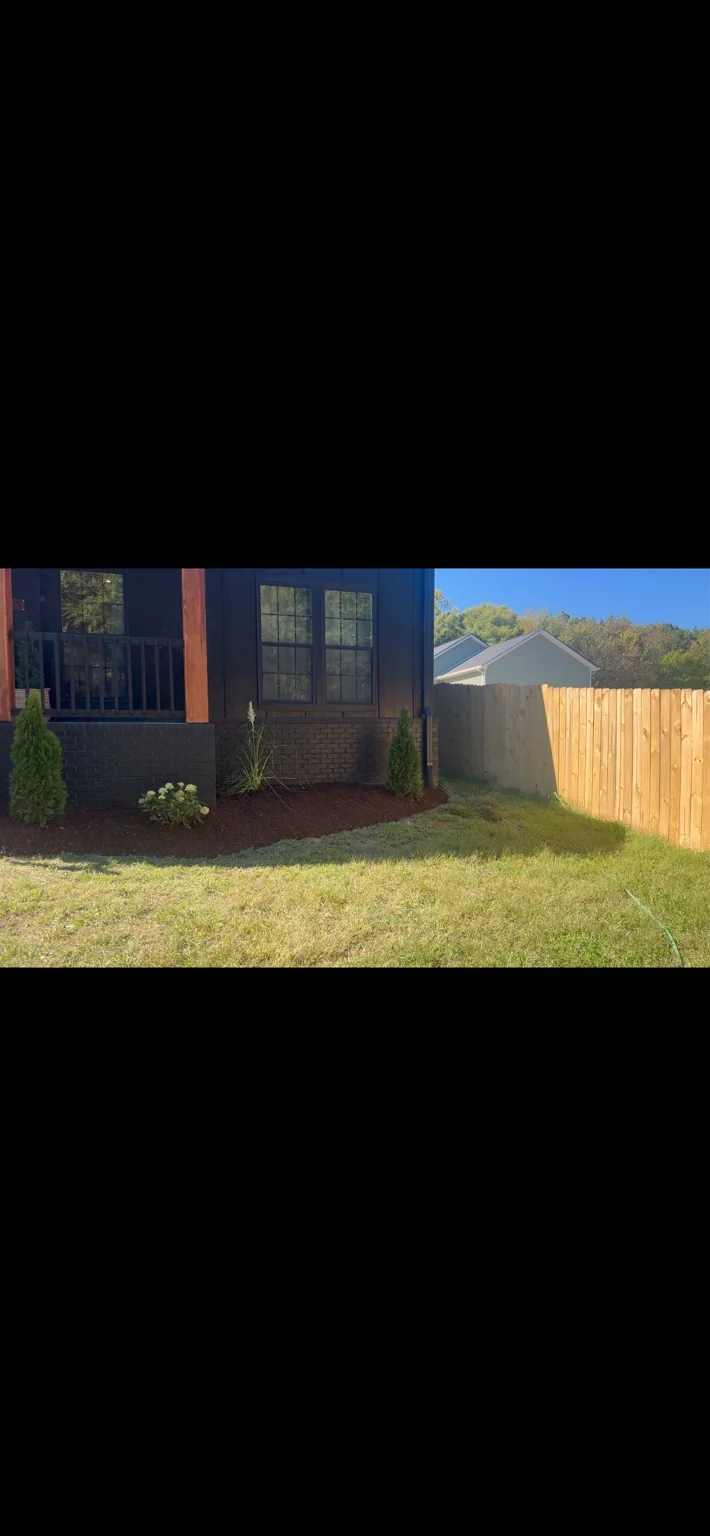 Planting bed along a home and wooden fence