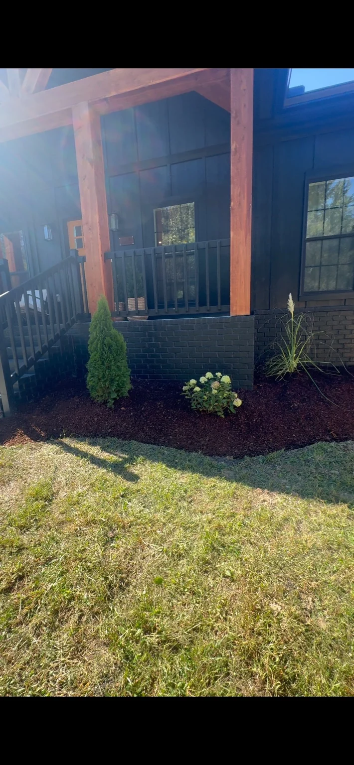 New plants in a mulched bed beside a porch
