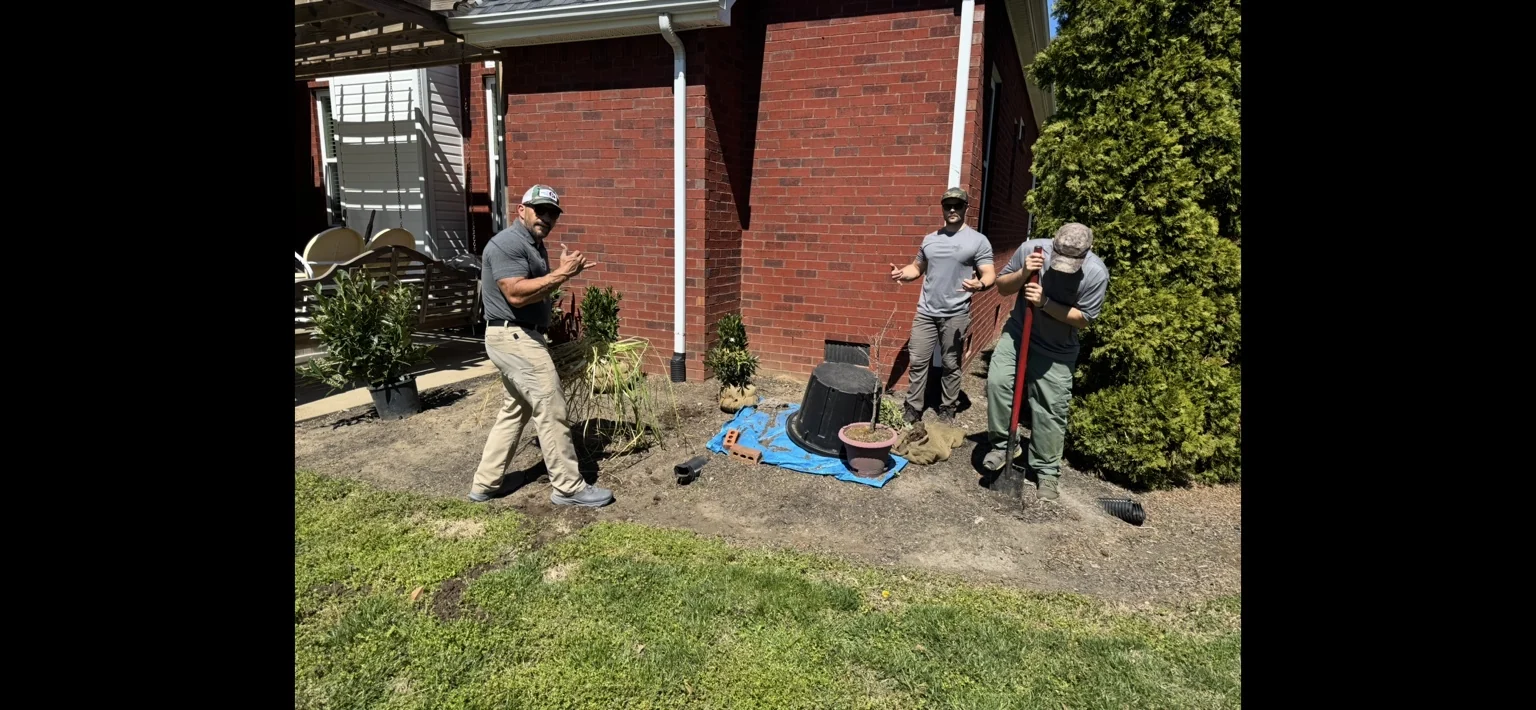 Landscaping crew working with plants beside a brick home
