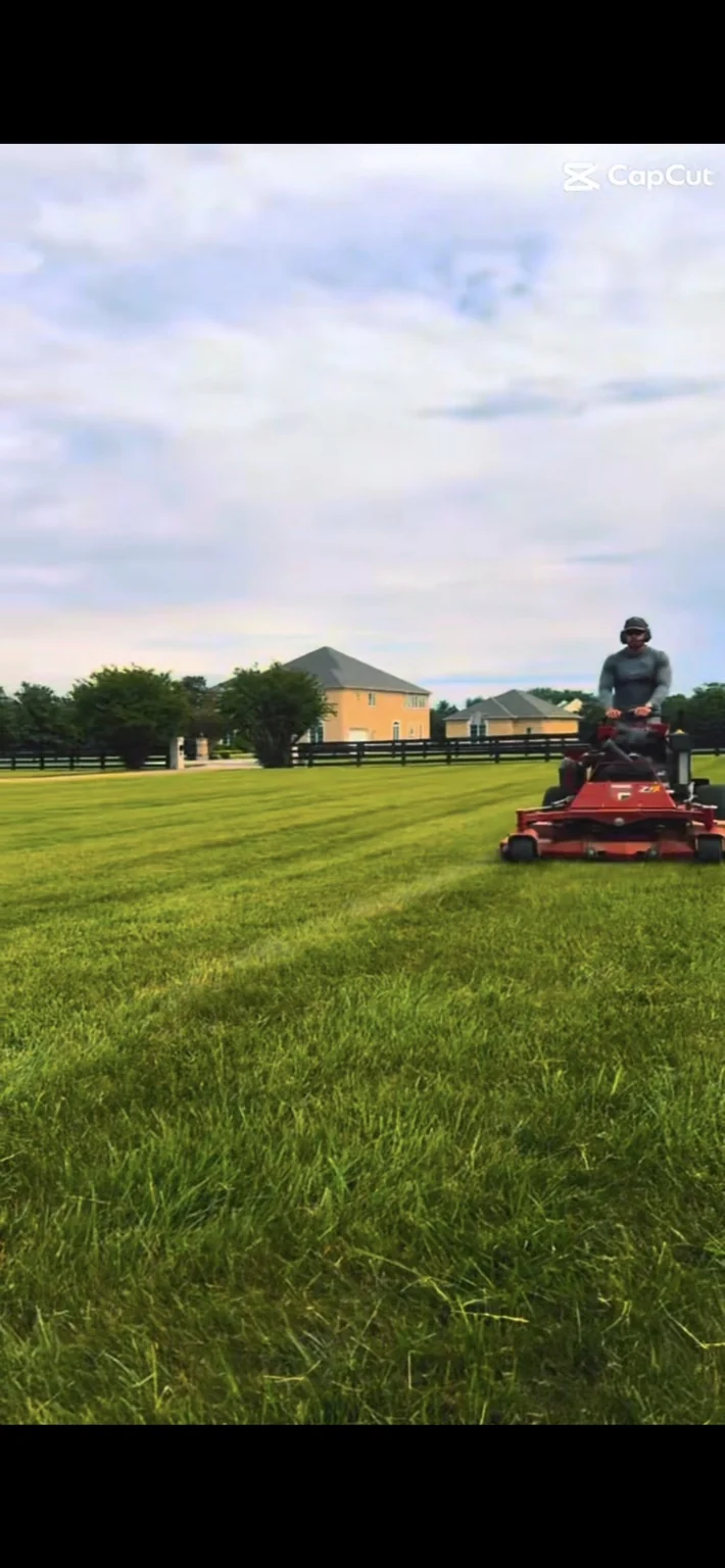 Lawn-care crew member mowing a striped lawn