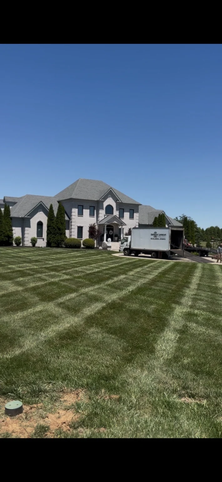 Striped lawn in front of a home with an American Landscape truck