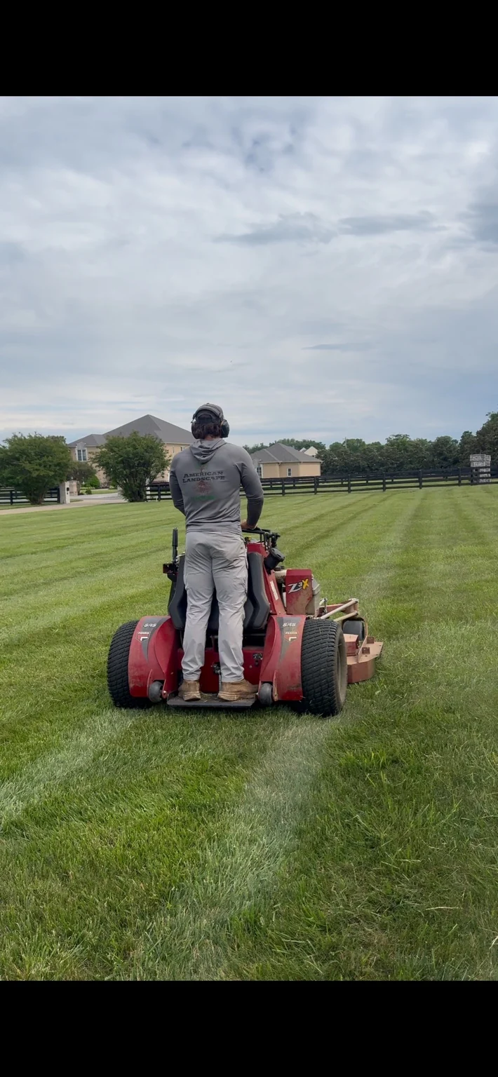 Lawn-care crew member using a riding mower