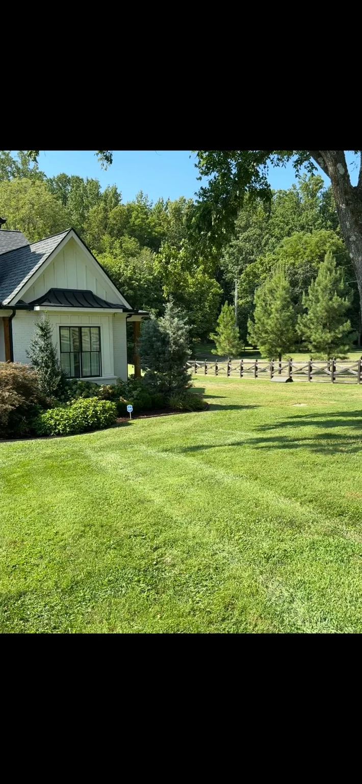 Mowed yard beside a home and a wooden fence